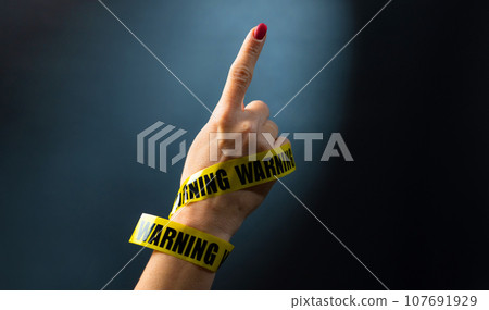 Hand with warning tape shows signs Hand with warning tape shows signs 107691929