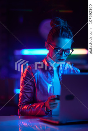 modern woman in glasses with laptop using smartphone modern woman in glasses with laptop using smartphone 107692560