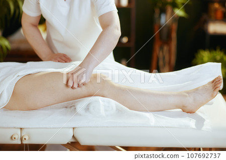Closeup on massage therapist in spa salon massaging clients leg Closeup on massage therapist in spa salon massaging clients leg 107692737