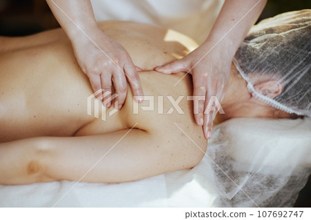 Medical massage therapist in massage cabinet massaging client Medical massage therapist in massage cabinet massaging client 107692747