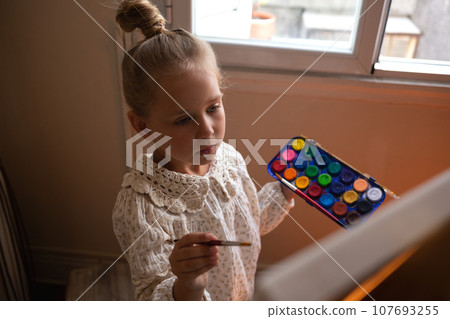 little cute girl draws with paints on canvas at the easel little cute girl draws with paints on canvas at the easel 107693255