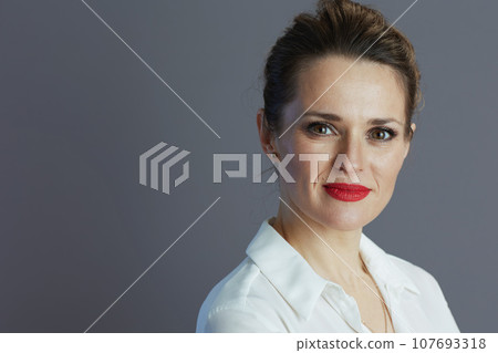 elegant woman worker in white blouse against gray background 107693318
