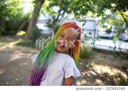portrait of a little beautiful girl with multi-colored african braids 107693349
