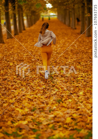 woman in fitness clothes in park jogging woman in fitness clothes in park jogging 107693735