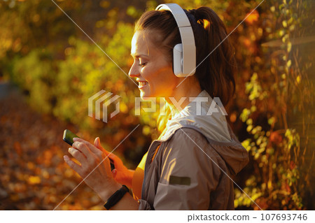 smiling elegant woman in park listening to music smiling elegant woman in park listening to music 107693746