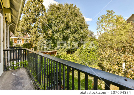 a balcony with trees in the back and bushes on the other side of the house, as seen from outside a balcony with trees in the back and bushes on the other side of the house, as seen from outside 107694584