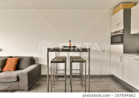 a living room with a couch, coffee table and small kitchen area in the back wall is white painted walls a living room with a couch, coffee table and small kitchen area in the back wall is white painted walls 107694862