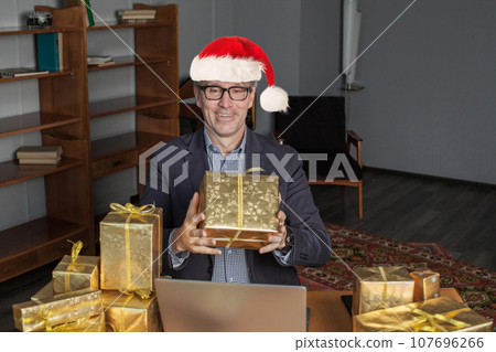 Handsome businessman Santa with gift box surprise present in office. Christmas  107696266