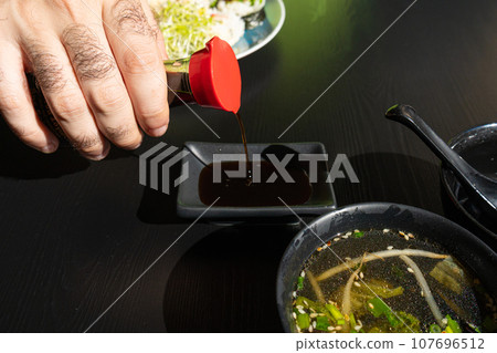 Pouring Soy Sauce in Japanese Ceramic Bowl in Sushi Restaurant 107696512