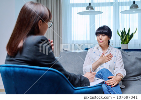 Mature 50s woman having therapy session with psychologist, in office Mature 50s woman having therapy session with psychologist, in office 107697041