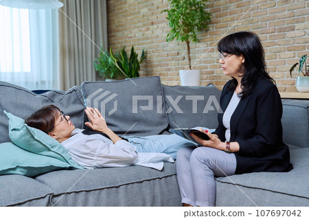 Female psychologist having therapy with middle-aged woman patient in office Female psychologist having therapy with middle-aged woman patient in office 107697042