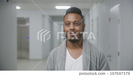 Happy African American man stands in hospital corridor 107697379
