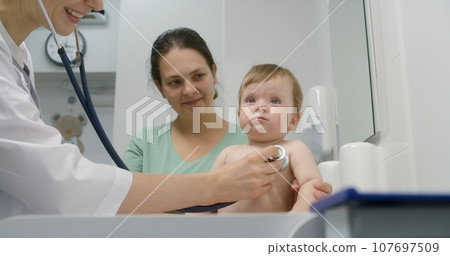 Baby sits on changing table in hospital room 107697509