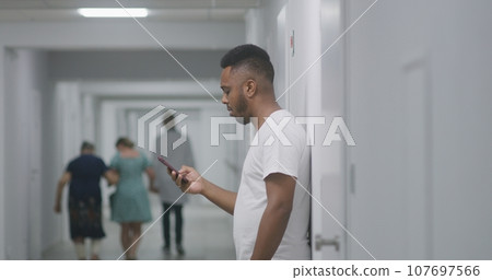 Patient records voice message and surfs the Internet using phone in clinic corridor 107697566