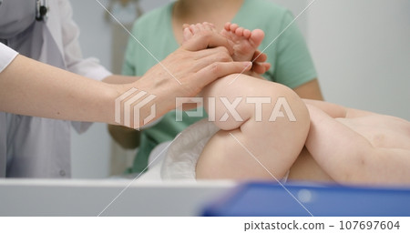 Close up of doctor checking development of hip joints of baby 107697604