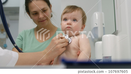 Baby sits on changing table in hospital room 107697605