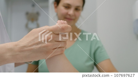 Close up of doctor checking development of hip joints of baby 107697627