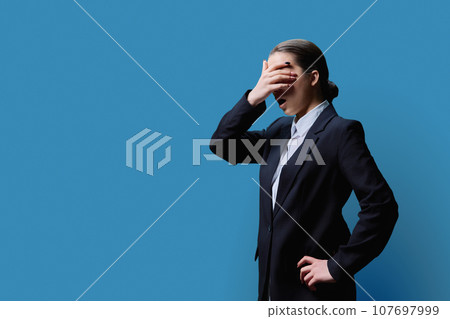 Shocked teenage girl looking at copy space, blue studio background, covering face with hands Shocked teenage girl looking at copy space, blue studio background, covering face with hands 107697999