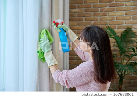 Close-up of woman in gloves cleaning curtains 107698001