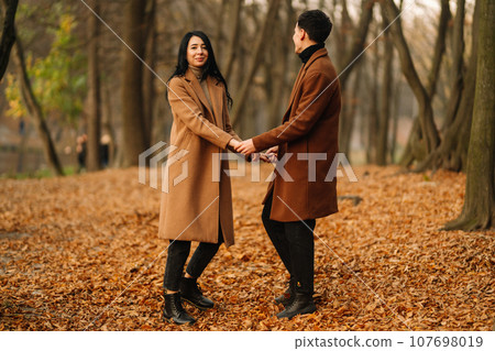 Young couple in love walking in the park on a autumn day. Enjoying time together. 107698019