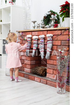 A young child plays by the fireplace during the Christmas season A young child plays by the fireplace during the Christmas season 107698180