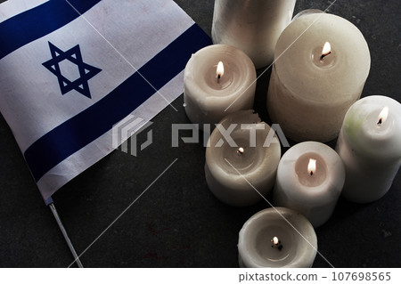 Burning candles and flag of Israel on dark background. Holocaust remembrance day Burning candles and flag of Israel on dark background. Holocaust remembrance day 107698565