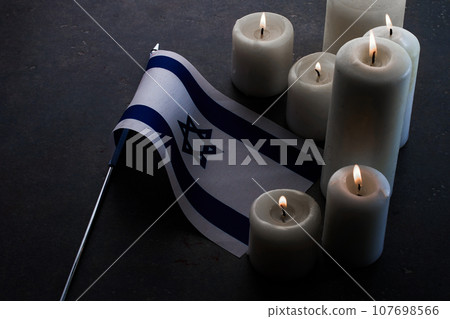 Burning candles and flag of Israel on dark background. Holocaust remembrance day Burning candles and flag of Israel on dark background. Holocaust remembrance day 107698566