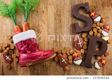 Dutch holiday Sinterklaas background. Children shoe with carrots, traditional sweets and chocolate letter 107698588