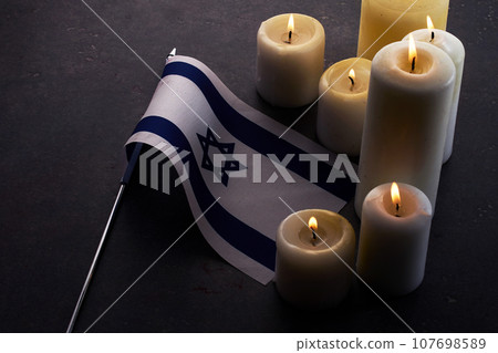 Burning candles and flag of Israel on dark background. Holocaust remembrance day Burning candles and flag of Israel on dark background. Holocaust remembrance day 107698589