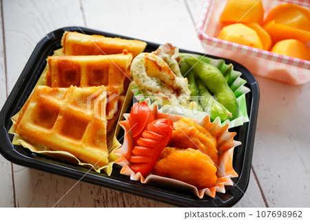 我把華夫餅放在小學四年級女兒的午餐盒裡。甜點是柿子。 107698962