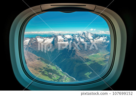 View from the airplane illuminator, mountains covered with snow 107699152