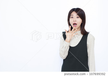 一個三十多歲的女人，在白色背景前感到驚訝 107699392