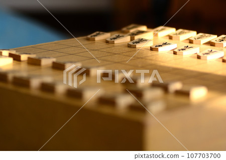 Shogi pieces lined up on a shogi board in bright light Shogi pieces lined up on a shogi board in bright light 107703700