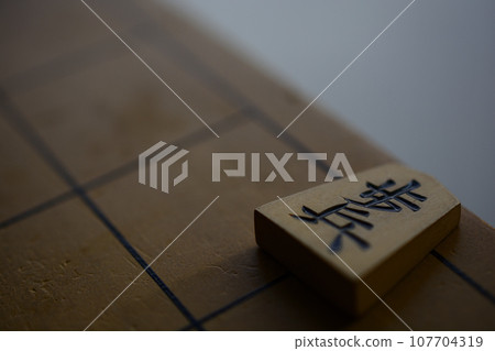 Shogi board and infantry pieces in a dark room 107704319