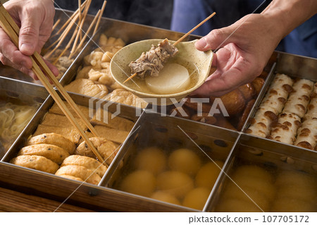 A cook scooping hot oden with chopsticks A cook scooping hot oden with chopsticks 107705172