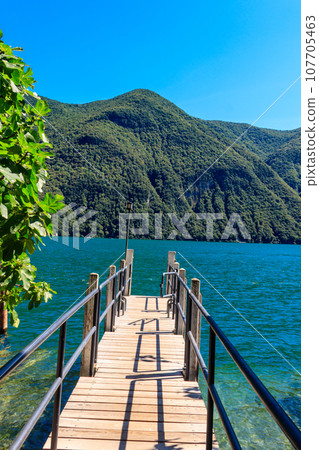 Wooden pier overlooking the Alps and Lake Lugano in Switzerland 107705463