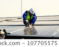 Maintenance technicians installing solar panels at solar cell farm 107705575