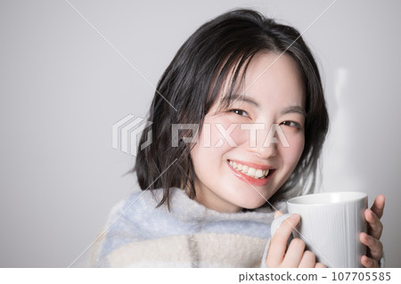 Young woman holding a mug, image of sensitivity to cold and winter, close-up 107705585