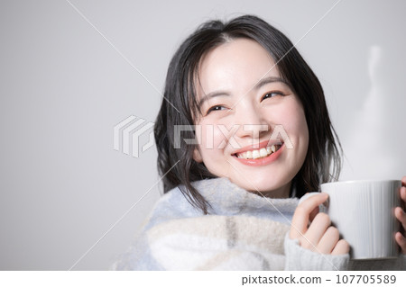 Young woman holding a mug - image of sensitivity to cold and winter Young woman holding a mug - image of sensitivity to cold and winter 107705589