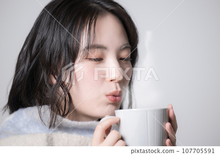 拿著杯子的年輕女子 — 對寒冷和冬天敏感的形象 拿著杯子的年輕女子 — 對寒冷和冬天敏感的形象 107705591