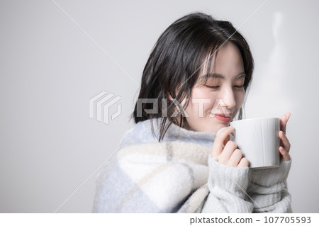 拿著杯子的年輕女子 — 對寒冷和冬天敏感的形象 107705593