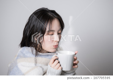 拿著杯子的年輕女子 — 對寒冷和冬天敏感的形象 107705595