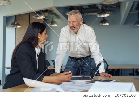 Two business managers working with project documents while sitting in office  107708106