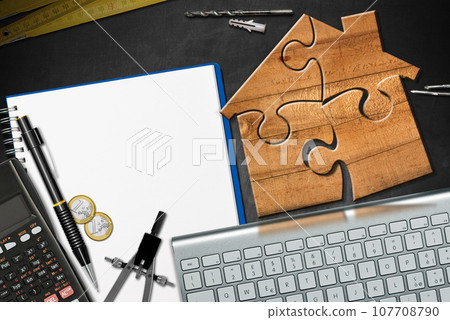 Wooden House made of Jigsaw Puzzle Pieces on a Desk 107708790