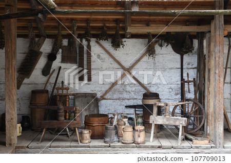 Collection of planers and retro wood saws hang on a wooden wall near an old house. Carpenters plane and other things on wall 107709013