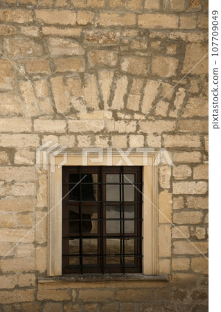 Very old window in brick stone wall of castle or fortress of 18th century. Full frame wall with window Very old window in brick stone wall of castle or fortress of 18th century. Full frame wall with window 107709049