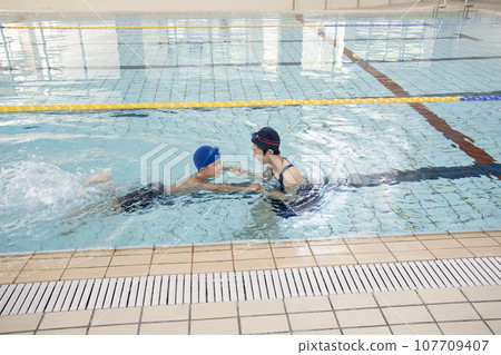 游泳教練牽著男孩的手在泳池裡 107709407