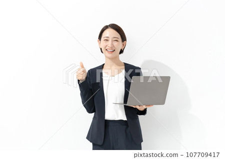 拿著膝上型計算機和做一個好標誌的微笑的女商人 拿著膝上型計算機和做一個好標誌的微笑的女商人 107709417