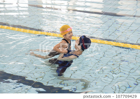 游泳教練牽著女孩的手在泳池裡 游泳教練牽著女孩的手在泳池裡 107709429