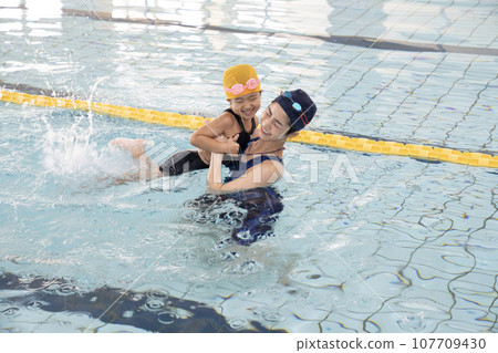 Swimming coach leading a girl's hand in the pool 107709430